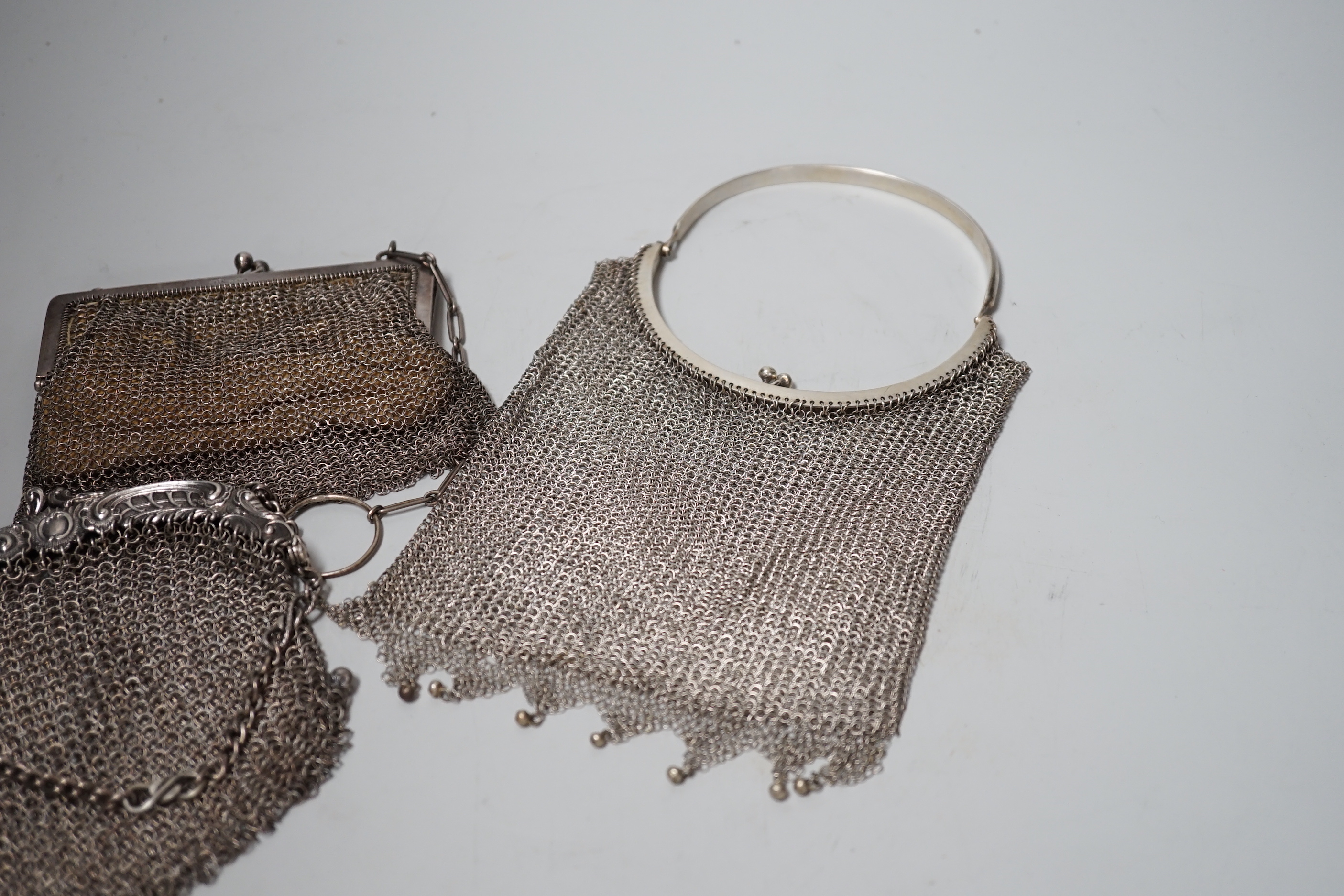A George V silver gilt mesh evening bag, retailed by Mappin & Webb, Birmingham, 1916 and a smaller silver evening bag, a Chinese white metal mesh evening bag, maker LH and a German 900 standard white metal mesh evening b